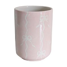 a pink and white vase with bows on the outside, sitting in front of a white background