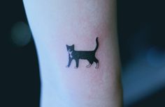 a small black cat tattoo on the arm