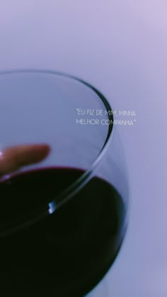 a hand reaching for a glass of red wine in front of a white background with text