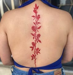 the back of a woman's shoulder with red flowers on it and leaves in the center