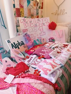 a bed covered in lots of pink and white clothing next to a sign that says, thank