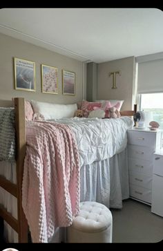 a white bed sitting next to a window covered in pink and white blankets on top of a wooden frame