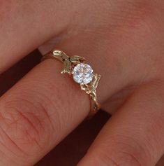 a woman's hand with a gold ring on it and a diamond in the middle