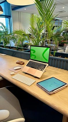 an open laptop computer sitting on top of a wooden desk next to a phone and tablet