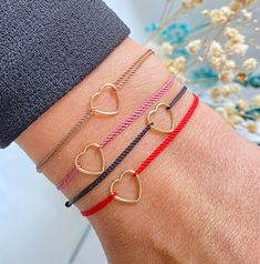 three different bracelets with hearts on the wrist and one is red, white, and gold