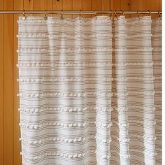 a white shower curtain hanging on a wooden wall