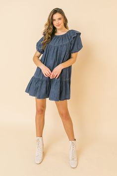 A lightweight denim mini dress featuring round neckline, ruffle at shoulder, puff sleeve, ruffled hemline and keyhole button closure Details Self: 100% Cotton Size & Fit - Model is 5`8" And Wearing Size Small - Measurements Taken From Size Small - Approx. Length: 30.5" Blue Casual Mini Hem Dress, Cotton Mini Hem Dress For Brunch, Cotton Mini Hem Dress With Ruffles, Cotton Ruffle Dress With Mini Hem, Short Sleeve Cotton Mini Dress For Brunch, Cotton Mini Hem Dress For Spring, Cotton Mini Dress With Ruffles, Dark Wash Denim Mini Dress For Day Out, Cotton Mini Dress For Day Out