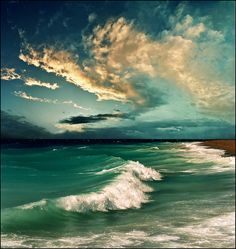 an ocean scene with waves and clouds in the sky