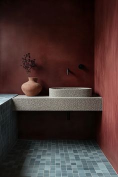 a bathroom with red walls and a sink in the corner, next to a window