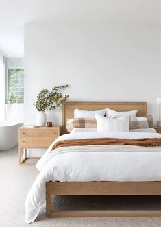 a bed with white linens and pillows in a bedroom next to a bathtub