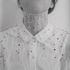 a woman wearing a white shirt with red beads on the collar and neckline is shown in black and white