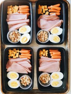 four trays filled with different types of food including eggs, ham, and carrots