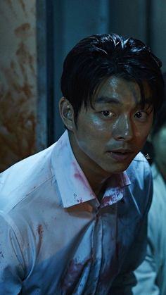 a man with blood all over his shirt and tie is staring at something in the distance