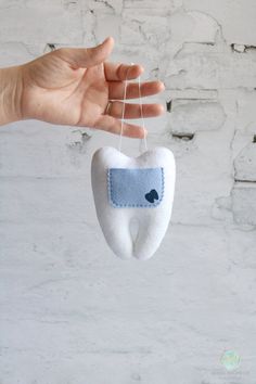 a hand is holding a tooth shaped ornament