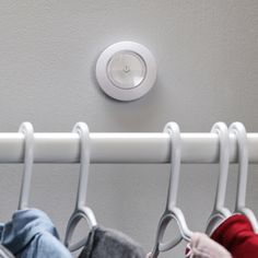 three coats hang on hooks in front of a light switch