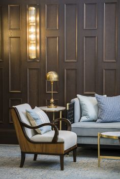 a living room with two couches, chairs and a table in front of wooden paneled walls