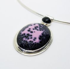 This sterling silver necklace is exquisitely enamelled in pink and black with a black onyx detail in the bail. The focal enamelled element features a beautiful constellation of black and pink colors which I've bezel set in sterling and fine silver with a bee cutout in the back. The bail is a sterling silver tube with a bezel set black onyx which is riveted to the back of the focal piece. The chain is a 16" italian silver omega necklace.This is a fun and unique abstract piece.Browse the Gracebour Silver Necklace With Black Enamel In Distinctive Style, Unique Black Enamel Pendant Necklace, Sterling Silver Pendant Necklace With Black Enamel, Unique Black Oval Pendant Necklace, Unique Black Cabochon Necklace, Handmade Black Enamel Necklace, Bee Cutout, Omega Necklace, Enamel Necklaces