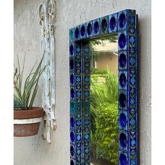 a mirror sitting on the side of a wall next to a potted plant