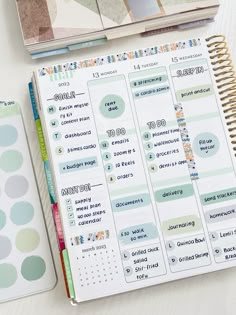 an open planner next to a notebook with stickers on it