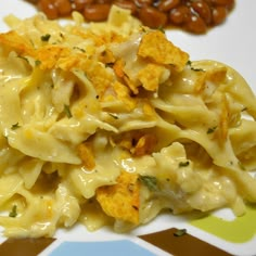 a white plate topped with macaroni and cheese covered in sauce next to beans