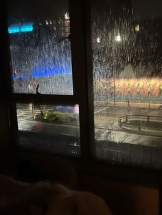 two windows with rain falling on them in the night time, and one window is open