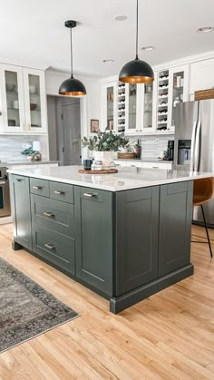 A dark green painted kitchen island with wooden accents and black and gold pendant lights. Painted Kitchen Island, Green Kitchen Island, Dark Green Kitchen, Kitchen Island Cabinets, Kabinet Dapur, Kitchen Cabinets Ideas, Green Kitchen Cabinets, Cabinets Ideas, New House - Kitchen