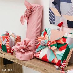 many wrapped presents are sitting on a wooden shelf in front of paintings and wall hangings