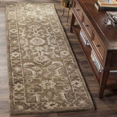 a brown and beige area rug on a wooden floor in a living room next to a dresser