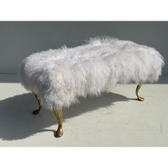 a white bench with gold legs and fur on it