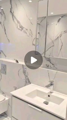 a white bathroom with marble walls and flooring is featured in this video by the company