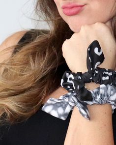 a close up of a woman wearing a black and white scarf around her neck with a bow on it