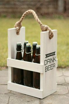 a wooden crate filled with beer bottles sitting on top of a stone floor next to grass