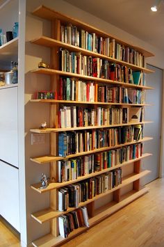 a bookshelf filled with lots of books on top of a hard wood floor