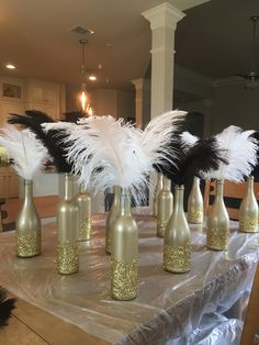 there are many bottles with feathers in them on the table