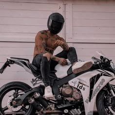 a man sitting on top of a motorcycle in front of a garage door wearing a helmet