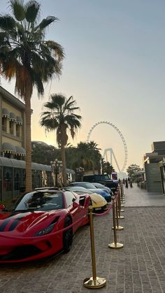 a row of cars parked next to each other on a brick road near palm trees