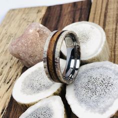 a wooden ring with an antler wood inlay on it sitting on top of some rocks