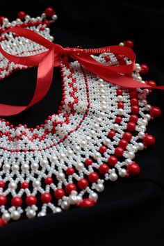 red and white beaded necklace with ribbon on black background