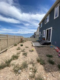 an empty yard in front of a house on a sunny day with blue sky and clouds