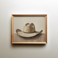 an oil painting of a cowboy hat on a white wall next to a brown frame