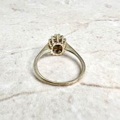 Vintage 10 karat yellow gold halo ring centering an oval sapphire simulant blue stone (glass) measuring 5.5 x 4 mm. It is haloed with 12 single cut diamonds weighing approximately 0.18 carat. The diamonds are approximately I-J color and SI2-I1 in clarity. This ring is a size 6.25 US / M UK / 52 FR. > Resizing not included. This ring can be resized to fit most fingers. Please contact us for details. Resized rings are final sale. Stamped 10K IK. It weighs 1.9 gram. Ring width: 9.6 mm. Band with: 1 Vintage Yellow Gold Crystal Ring With Gemstone, Vintage Yellow Gold Carnelian Ring, Gold Vintage Sapphire Cabochon Ring, Vintage Yellow Gold Gemstone Cabochons, Edwardian Style Engagement Ring, Gold Halo Ring, December Birthstone Jewelry, Gemstone Rings Vintage, Gold Chain Earrings