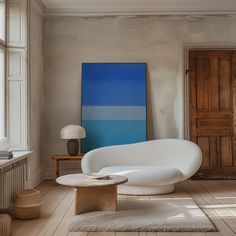 a living room with a large painting on the wall next to a white couch and coffee table