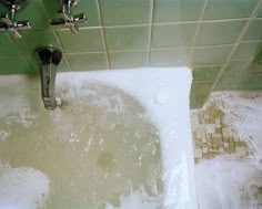 a bathtub filled with foam and water next to a faucet