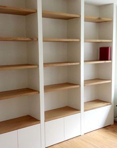 empty bookshelves in an empty room with hard wood flooring and white walls