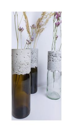 three vases with flowers in them sitting next to each other on a white surface