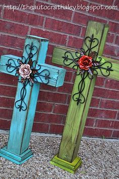 two wooden crosses sitting next to each other in front of a brick wall with flowers on them