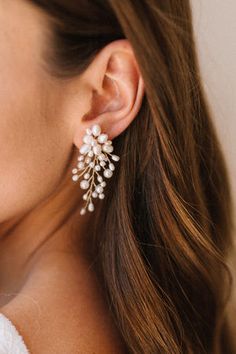 a close up of a woman's ear wearing earrings with pearls and leaves on them