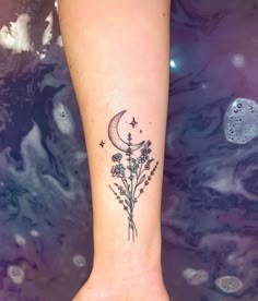 a tattoo on the foot of a woman with flowers and a moon in the sky