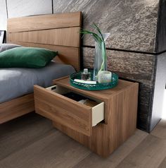 a bed room with a neatly made bed and a vase on the nightstand next to it