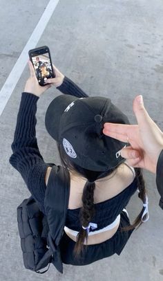 a person sitting on the ground holding up their cell phone to take a selfie